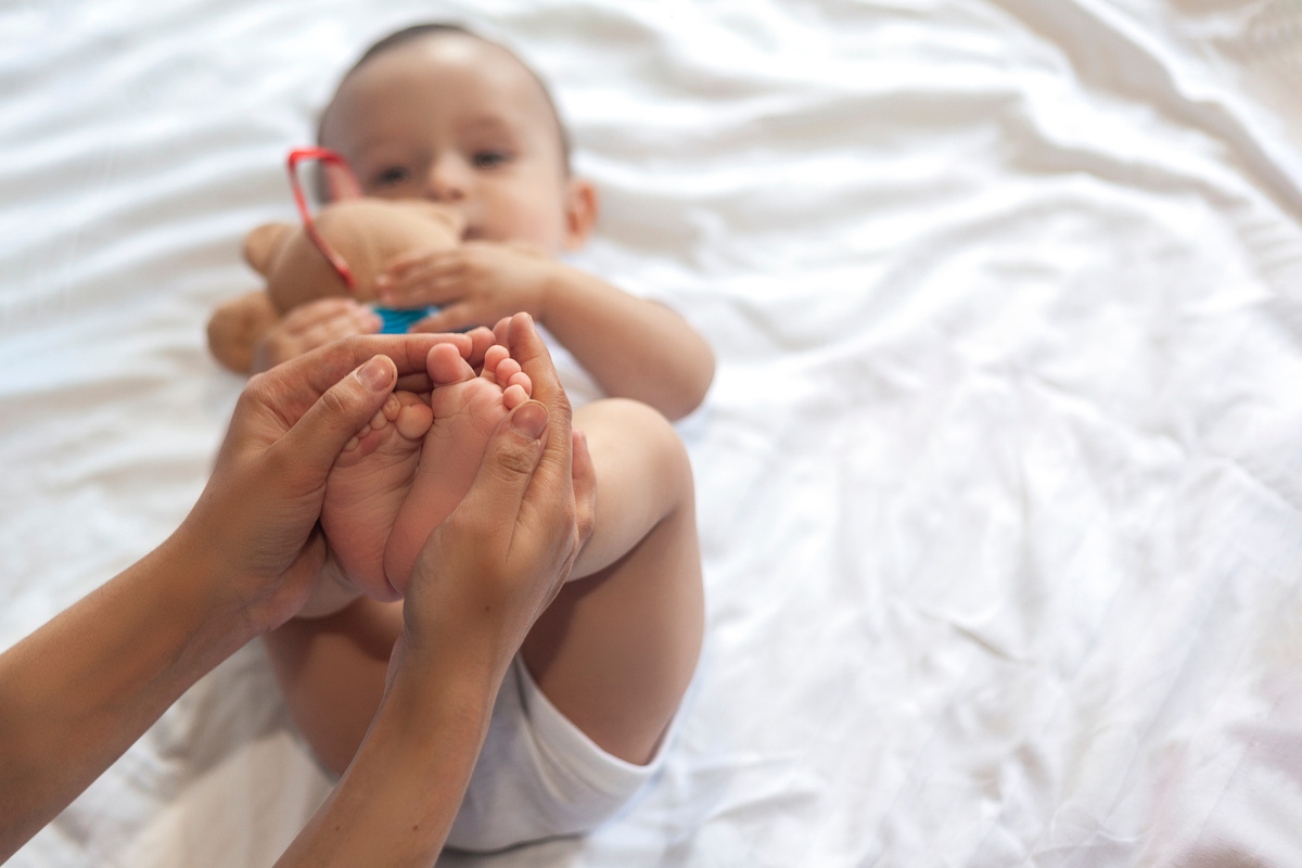 Baby Massage. Mom Doing Gymnastics with Kid. Mommy Massaging Cute Baby Boy. Moving Baby's Legs to Help Relieve Constipation. Young Mother Doing Exercises and Movements to Stimulate Baby's Bowels.